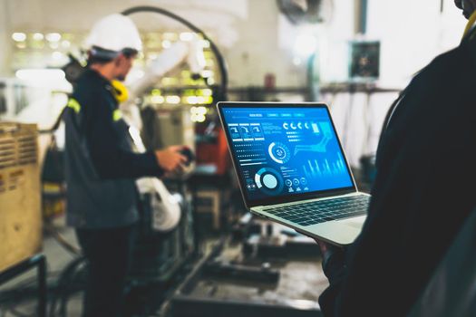 Factory workers working with adept robotic arm in a workshop . Industry robot programming software for automated manufacturing technology .