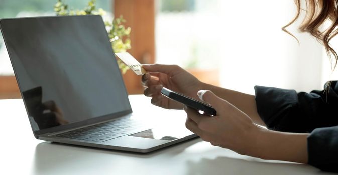 Asian woman checking online order details on smartphone Close control of credit card information entered..