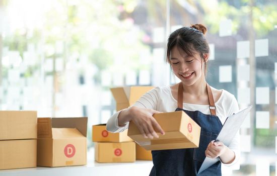 Starting small businesses SME owners female entrepreneurs Use a laptop or notebook to receive and review orders online to prepare to pack boxes, sell to customers, SME online business ideas..