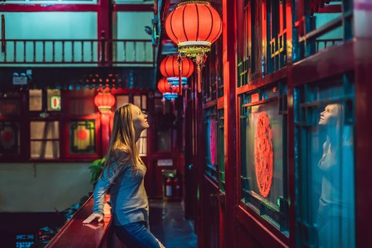 Young woman tourist looks at the Chinese traditional lanterns. Chinese New Year. Travel to China concept.