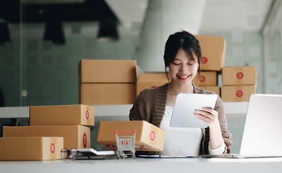 Startup small business entrepreneur SME, asian woman packing cloth in box. Portrait young Asian small business owner home office, online sell marketing delivery, SME e-commerce telemarketing concept.