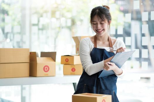 Starting small businesses SME owners female entrepreneurs Use a laptop or notebook to receive and review orders online to prepare to pack boxes, sell to customers, SME online business ideas..