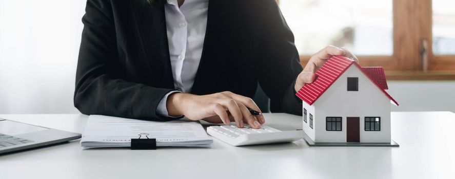 Woman accountant or bank worker uses calculator in the office to calculate house loan credit bureaucracy..