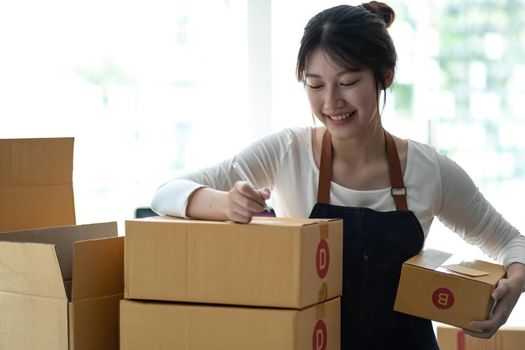 Portrait of Starting small businesses SME owners female entrepreneurs working on receipt box and check online orders to prepare to pack the boxes, sell to customers, sme business ideas online..