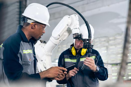 Factory workers working with adept robotic arm in a workshop . Industry robot programming software for automated manufacturing technology .