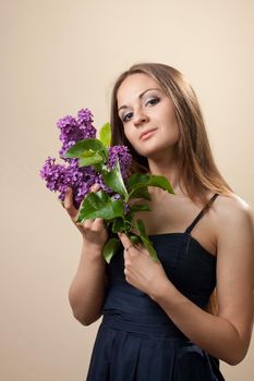 Beautiful young girl weared in black dress with a bouquet of lilac. Spring flowers concept.