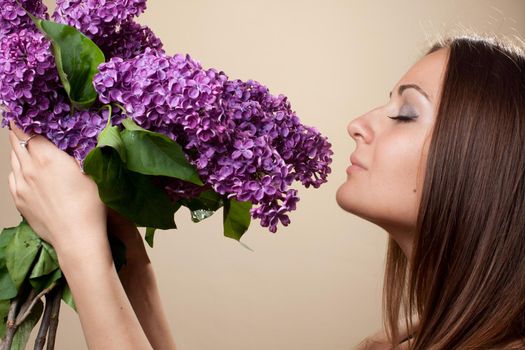 Beautiful young girl weared in black dress with a bouquet of lilac. Spring flowers concept.