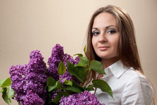 Beautiful young girl with a bouquet of lilac. Spring flowers concept.