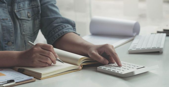 Close up asian woman working with financial data hand using calculator and writing make note with calculate. Business financial and accounting concept..