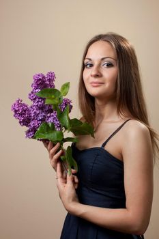 Beautiful young girl weared in black dress with a bouquet of lilac. Spring flowers concept.