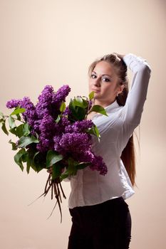 Beautiful young girl with a bouquet of lilac. Spring flowers concept.