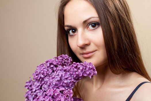 Beautiful young girl weared in black dress with a bouquet of lilac. Spring flowers concept.