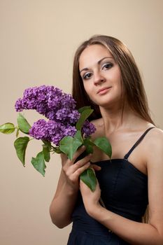 Beautiful young girl weared in black dress with a bouquet of lilac. Spring flowers concept.