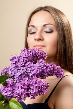 Beautiful young girl weared in black dress with a bouquet of lilac. Spring flowers concept.