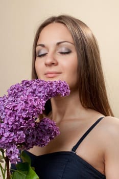 Beautiful young girl weared in black dress with a bouquet of lilac. Spring flowers concept.