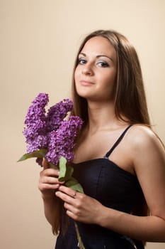 Beautiful young girl weared in black dress with a bouquet of lilac. Spring flowers concept.