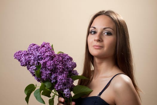 Beautiful young girl weared in black dress with a bouquet of lilac. Spring flowers concept.