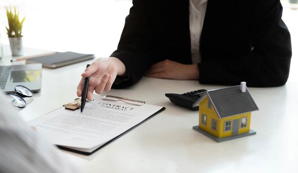 Home agents are explain to customers signing a contract to buy a new home..
