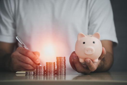 Man hand holding piggy bank on table, saving money wealth and financial concept, Business, finance, investment, Financial planning. Business financial saving for future concept.
