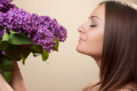 Beautiful young girl weared in black dress with a bouquet of lilac. Spring flowers concept.