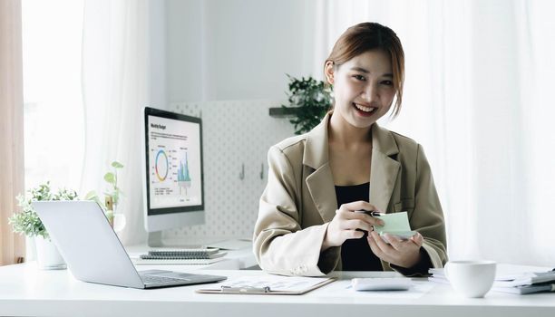 Portrait of confident young entrepreneur sitting at modern workplace and smiling to camera..