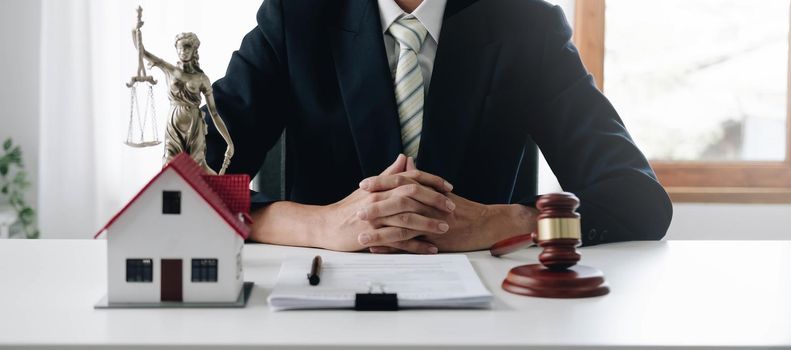 close-up photo of judge Wooden hammer and small wooden house on the table in the courtroom concept of real estate law property division Settlement and Divorce