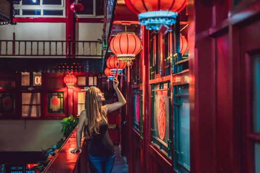 Young woman tourist looks at the Chinese traditional lanterns. Chinese New Year. Travel to China concept.