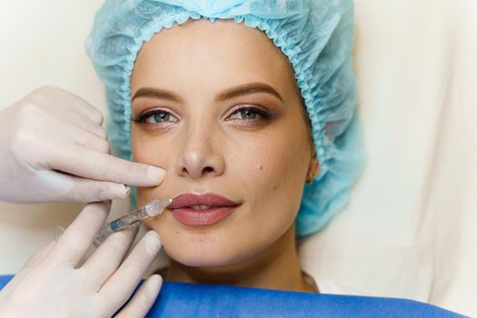 Lips augmentation injections for attractive girl. Plastic surgeon does injection in lip in medical clinic.