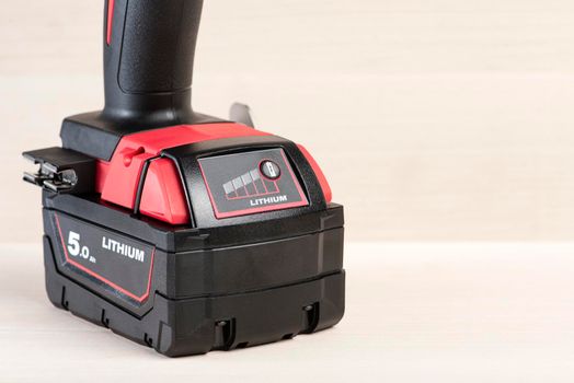 Battery for cordless drill. Screwdriver battery. Battery with a charge indicator lie on a wooden background.