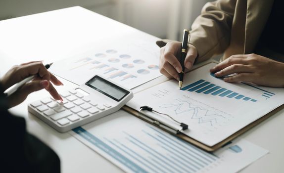 Close-up Hands of two young woman accountant use calculator with holding pen and point report in the office . finance and accounting concept.