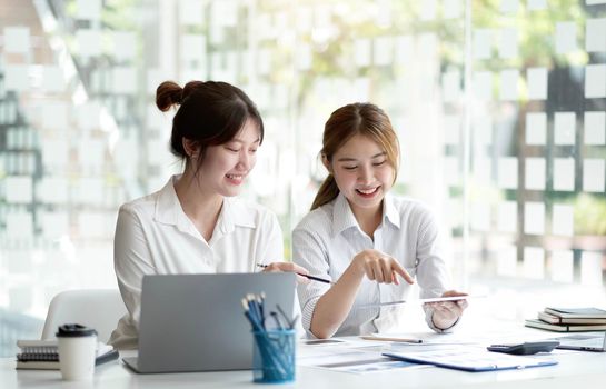 Two Young Asian businesswoman discuss with new startup project Idea presentation, analyze planning and financial statistics and investment market at office..