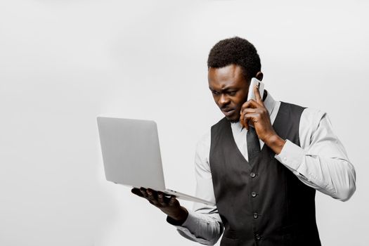 Influential african director speaks by phone and wathes to laptop. Solving business problems at home. On-line work at quarantine period covid 19.