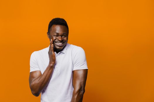 Funny black man jokes and smiles on orange background. Big discount for customers. Smiley people lifestyle. Advertise for online delivery services