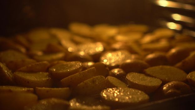 Rustic potatoes are baked in an oven. Potatoes with spices are fried in oil. Focus slide. 4k