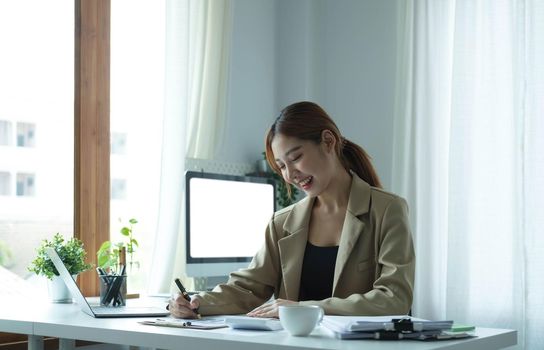 Young Asian businesswoman taking notes using a tablet at the modern office..