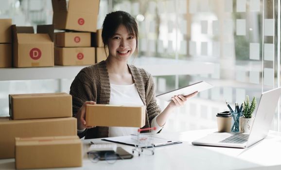 Startup small business entrepreneur SME, asian woman packing cloth in box. Portrait young Asian small business owner home office, online sell marketing delivery, SME e-commerce telemarketing concept.