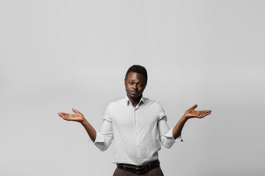 Handsome surprised black man shrugs and gives a choose. Choosing between 2 items. African offers a choice.