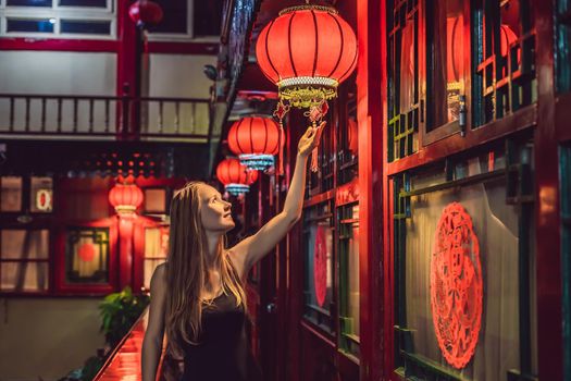 Young woman tourist looks at the Chinese traditional lanterns. Chinese New Year. Travel to China concept.