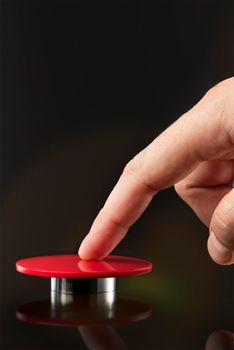 A man's hand presses a big red button. Red button on a dark background. The threat of using nuclear or chemical weapons of mass destruction. Rocket launch at the push of a button.