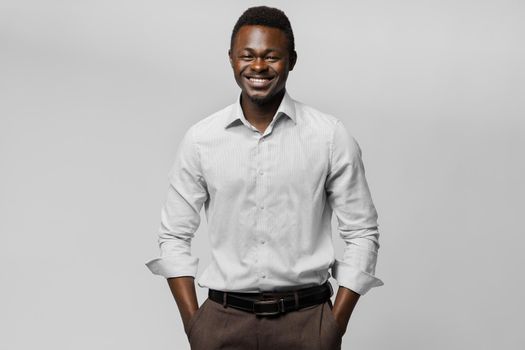 Black man in white shirt smiles on white background. Successful african businessman