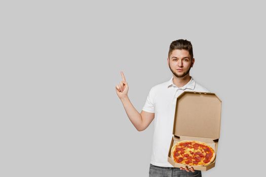 Online pizza safety delivery servise from restaurant. Young caucasian bearded courier points to advertise. Pizza with cheese boards.