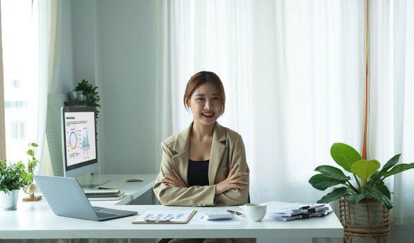 Portrait of confident young entrepreneur sitting at modern workplace and smiling to camera..