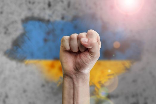 Support for Ukraine and solidarity. Help to the Ukrainian people in wartime. Fists as a symbol of support against the background of the Ukrainian flag. The concept of confrontation and struggle.