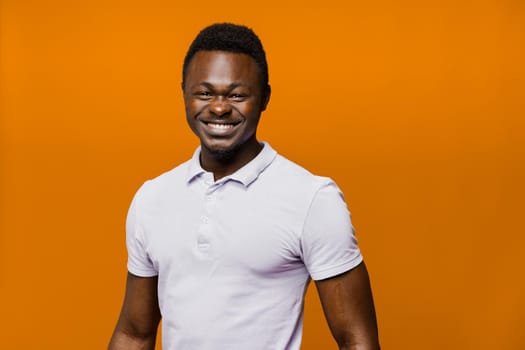 Handsome african smiles. Business portrait in studio on orange background. Online business