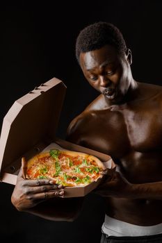 Fit surprised black man with pizza in cardboard box. Undressed handsome african man with pizza delivered to costumer.