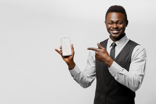 Black african business man points to his phone. Electronic store worker. Successful people lifestyle advert. You can win a prize in online bet.