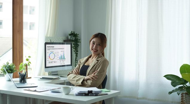 Portrait of confident young entrepreneur sitting at modern workplace and smiling to camera..