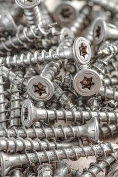 Close-up of universal silver screws with torx head. Self-tapping screws for wood, plywood or chipboard. Torx screws close up