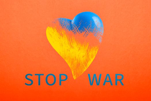 Stop war in Ukraine. Save Ukraine. The heart is painted in the colors of the Ukrainian flag - blue and yellow. No war text, poster on red background.