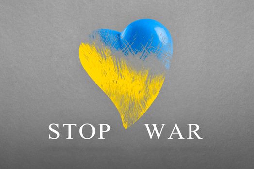 Stop war in Ukraine. Save Ukraine. The heart is painted in the colors of the Ukrainian flag - blue and yellow. No war text, poster on gray background.